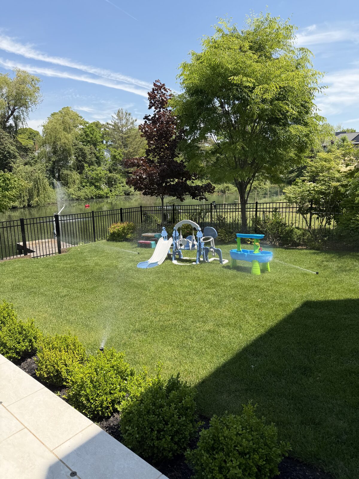 Lush backyard lawn with a play set beside the water