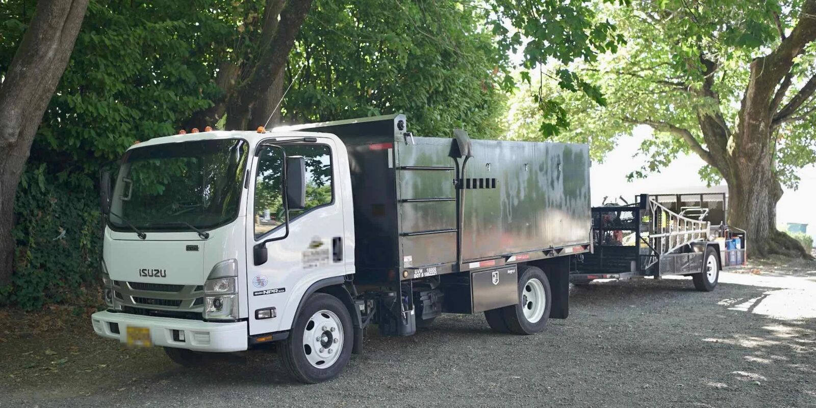 Landscaping truck and equipment trailer under the trees